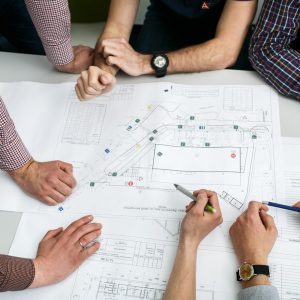 table-with-blueprints-hands-holding-pencils_1304-4272